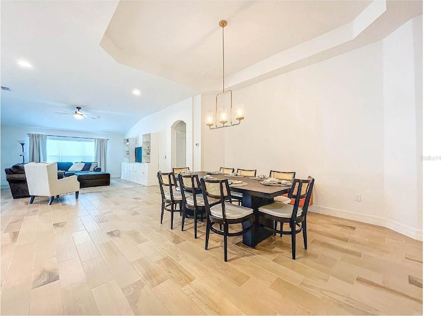 12010 Jackson Landing Pl, Tampa, FL 33624 - dining area featuring a chandelier, light wood-type flooring, ceiling fan, baseboards, and arched walkways