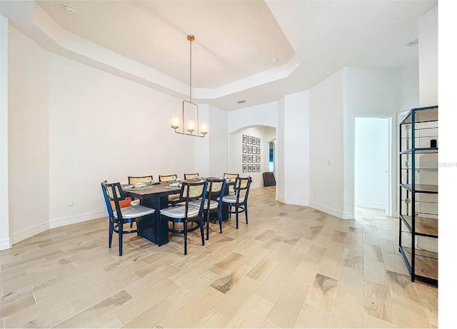 12010 Jackson Landing Pl, Tampa, FL 33624 - dining room with arched walkways, a raised ceiling, light wood-style floors, baseboards, and a chandelier