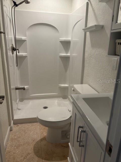 12055 4th St E, Treasure Island, FL 33706 - bathroom featuring a stall shower, toilet, a textured wall, vanity, and tile patterned flooring