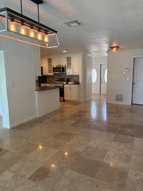 12055 4th St E, Treasure Island, FL 33706 - kitchen featuring stainless steel microwave, dark countertops, range with electric stovetop, glass insert cabinets, and white cabinetry
