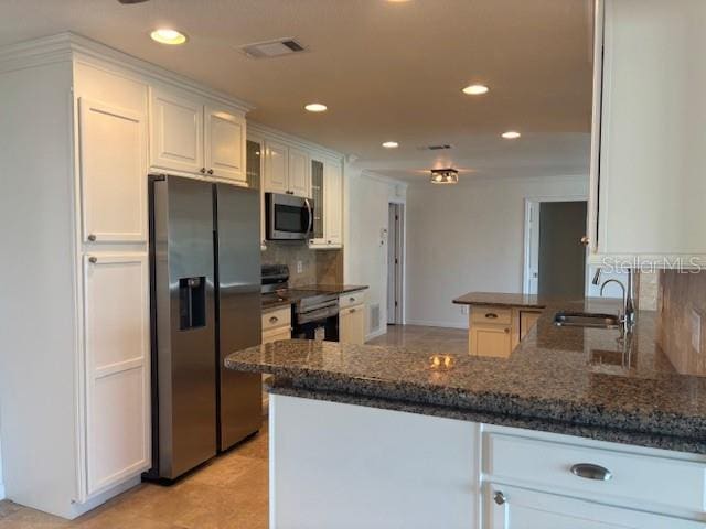 12055 4th St E, Treasure Island, FL 33706 - kitchen with stainless steel microwave, fridge with ice dispenser, electric range oven, backsplash, and white cabinetry