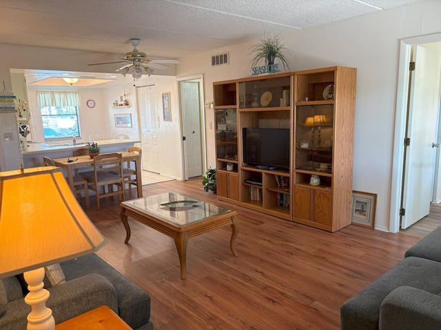 303 Meadow Ln, Oldsmar, FL 34677 - living room with wood finished floors, ceiling fan, baseboards, and a textured ceiling