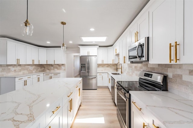 7607 22nd Ave W, Bradenton, FL 34209 - kitchen featuring stainless steel appliances, backsplash, white cabinets, hanging light fixtures, and light stone counters