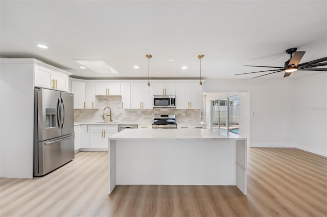 7607 22nd Ave W, Bradenton, FL 34209 - kitchen with stainless steel appliances, a sink, light wood-style floors, tasteful backsplash, and a center island
