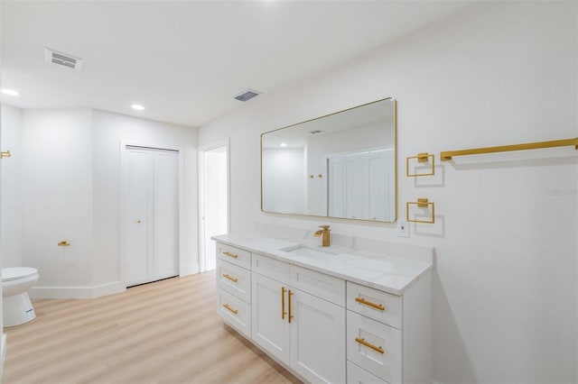 7607 22nd Ave W, Bradenton, FL 34209 - bathroom with wood finished floors, toilet, vanity, recessed lighting, and baseboards