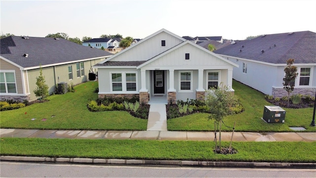 28547 Hillcrest Valley Blvd, Wesley Chapel, FL 33543 - view of front of house featuring board and batten siding, stone siding, central air condition unit, and a front lawn