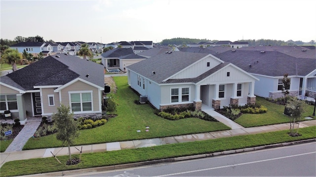 28547 Hillcrest Valley Blvd, Wesley Chapel, FL 33543 - view of front of house with a residential view, stone siding, a front yard, and central AC unit