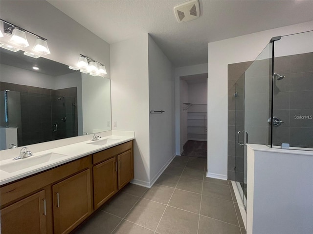 28547 Hillcrest Valley Blvd, Wesley Chapel, FL 33543 - full bathroom with a shower stall, tile patterned floors, double vanity, a walk in closet, and baseboards