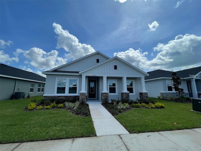 28547 Hillcrest Valley Blvd, Wesley Chapel, FL 33543 - craftsman house featuring stone siding, a front yard, board and batten siding, and central AC