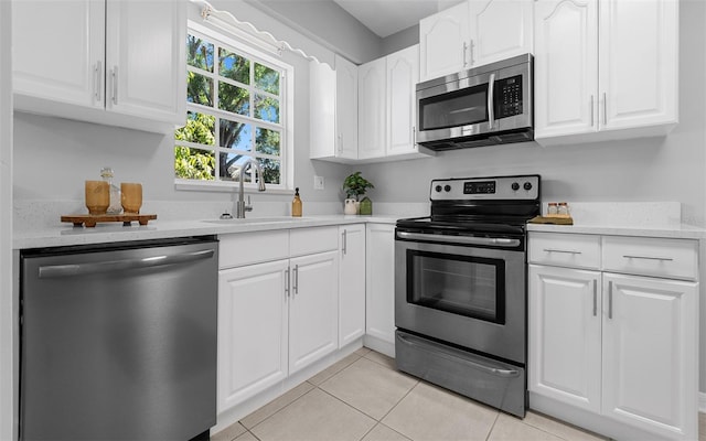 2613 E 113th Ave, Tampa, FL 33612 - kitchen featuring appliances with stainless steel finishes, a sink, white cabinets, and light tile patterned floors