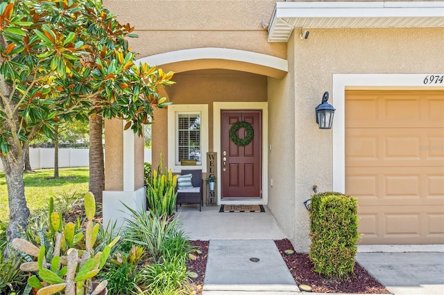 6974 Holly Heath Dr, Riverview, FL 33578 - doorway to property with stucco siding, an attached garage, and covered porch