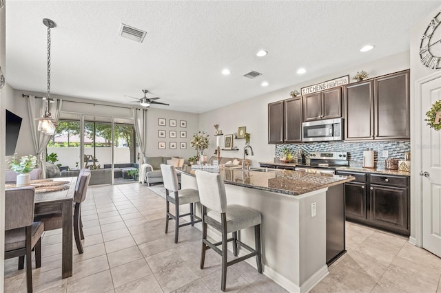 6974 Holly Heath Dr, Riverview, FL 33578 - kitchen with appliances with stainless steel finishes, a breakfast bar area, a ceiling fan, a sink, and decorative backsplash