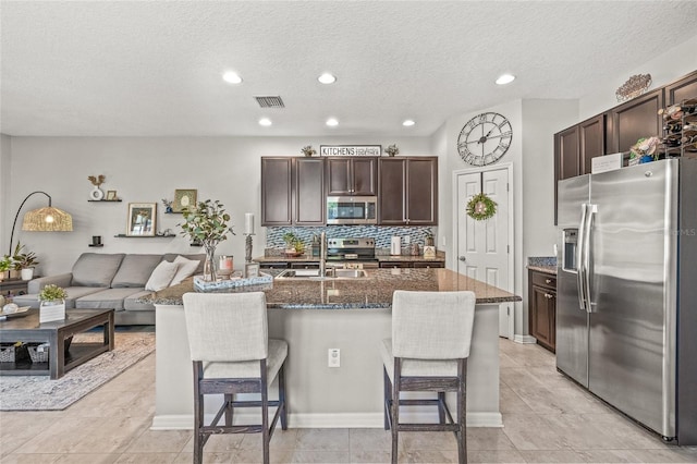6974 Holly Heath Dr, Riverview, FL 33578 - kitchen featuring stainless steel appliances, a sink, a breakfast bar, dark brown cabinets, and a kitchen island with sink