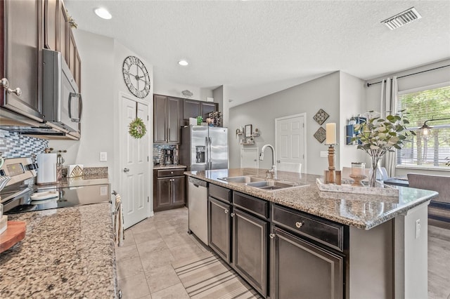 6974 Holly Heath Dr, Riverview, FL 33578 - kitchen featuring appliances with stainless steel finishes, a sink, a textured ceiling, backsplash, and light stone countertops