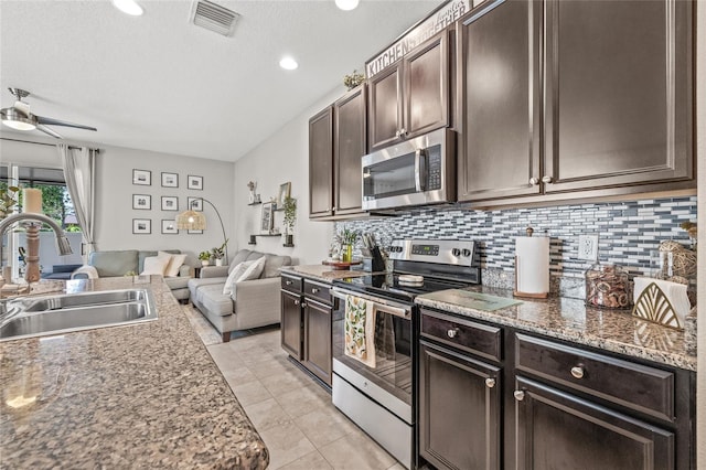 6974 Holly Heath Dr, Riverview, FL 33578 - kitchen featuring appliances with stainless steel finishes, open floor plan, a sink, dark brown cabinets, and tasteful backsplash
