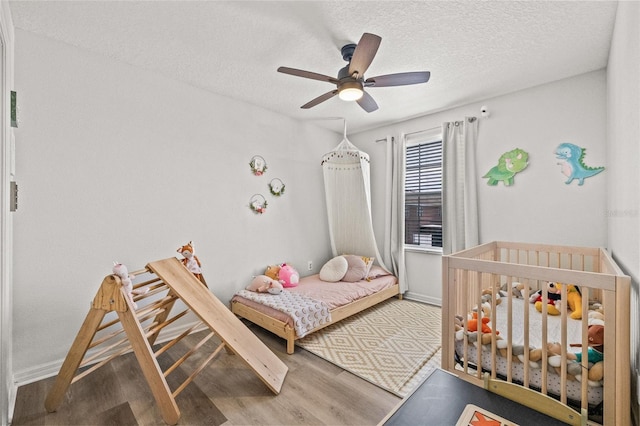 6974 Holly Heath Dr, Riverview, FL 33578 - bedroom featuring wood finished floors, a textured ceiling, a ceiling fan, and baseboards