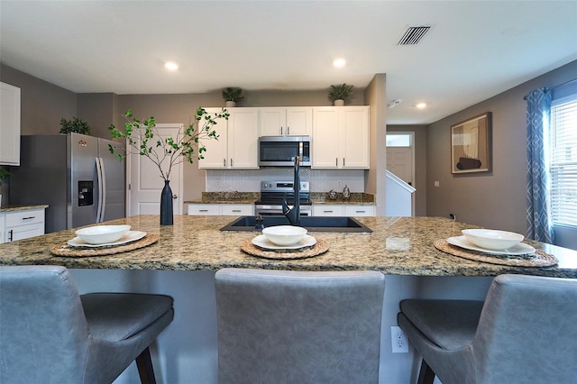 10826 Trailing Vine Dr, Tampa, FL 33610 - kitchen featuring stainless steel appliances, a breakfast bar area, a sink, white cabinets, and recessed lighting