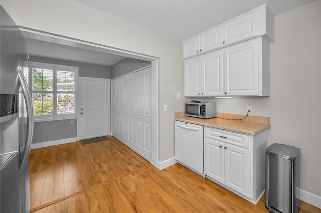 2073 Denmark St Unit 9, Clearwater, FL 33763 - kitchen featuring stainless steel appliances, light countertops, light wood-style floors, white cabinets, and a textured ceiling