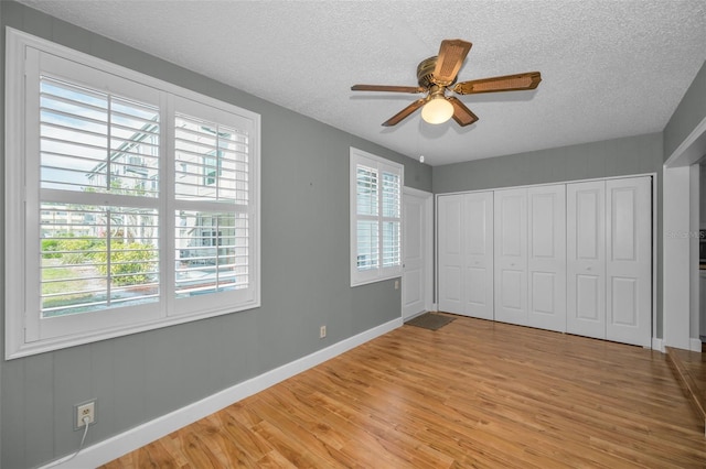 2073 Denmark St Unit 9, Clearwater, FL 33763 - unfurnished bedroom with light wood-type flooring, a textured ceiling, baseboards, ceiling fan, and a closet