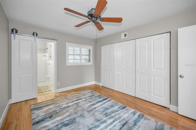 2073 Denmark St Unit 9, Clearwater, FL 33763 - unfurnished bedroom with baseboards, wood finished floors, a barn door, and a closet