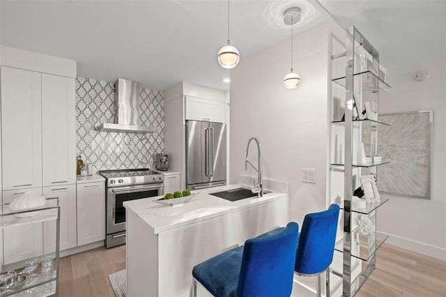 2620 Cove Cay Dr Unit 704, Clearwater, FL 33760 - kitchen featuring stainless steel appliances, wall chimney exhaust hood, a sink, decorative backsplash, and light wood finished floors