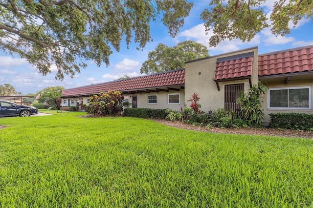 1701 Pinehurst Rd Unit 9G, Dunedin, FL 34698 - view of side of property with a tile roof, stucco siding, and a yard