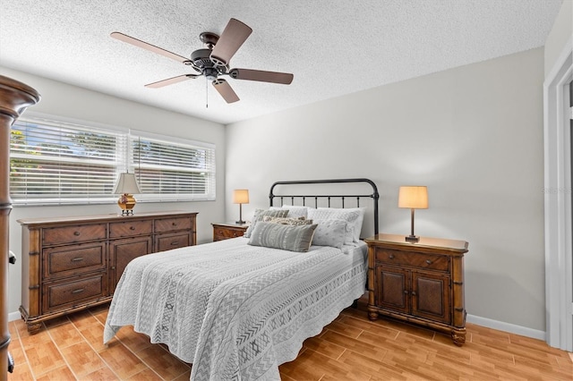 1701 Pinehurst Rd Unit 9G, Dunedin, FL 34698 - bedroom featuring light wood-style flooring, a textured ceiling, baseboards, and ceiling fan