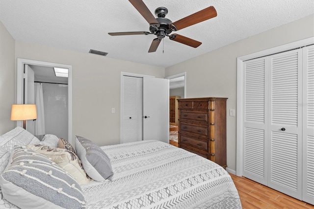 1701 Pinehurst Rd Unit 9G, Dunedin, FL 34698 - bedroom featuring multiple closets, light wood-type flooring, a textured ceiling, and a ceiling fan