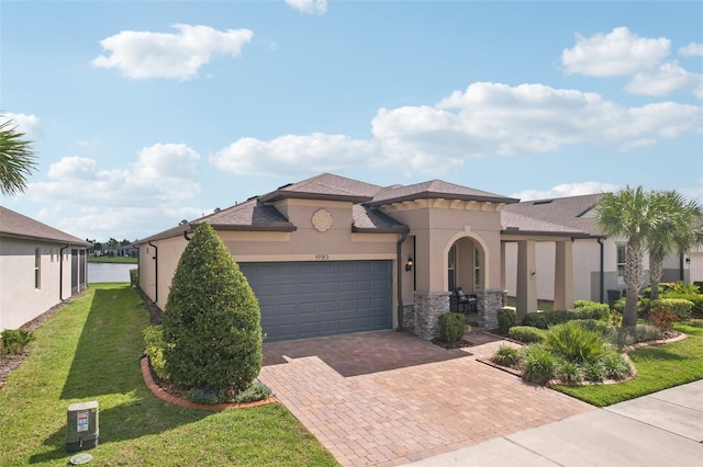 19183 Coastal Shore Ter, Land O Lakes, FL 34638 - mediterranean / spanish home featuring stucco siding, decorative driveway, a front lawn, an attached garage, and stone siding