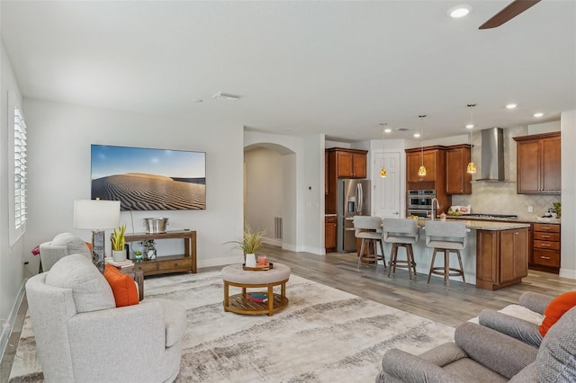 19183 Coastal Shore Ter, Land O Lakes, FL 34638 - living room with arched walkways, recessed lighting, a ceiling fan, light wood-style floors, and baseboards