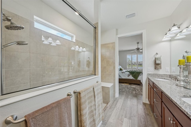 19183 Coastal Shore Ter, Land O Lakes, FL 34638 - full bath featuring wood finished floors, connected bathroom, a walk in shower, double vanity, and a ceiling fan