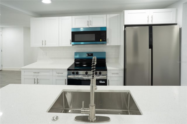 5510 12th St, Zephyrhills, FL 33542 - kitchen featuring appliances with stainless steel finishes, white cabinetry, decorative backsplash, recessed lighting, and baseboards