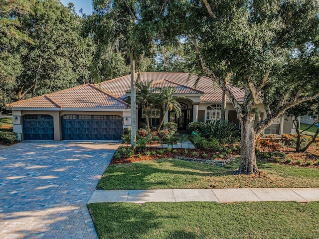 4962 Turtle Creek Trl, Oldsmar, FL 34677 - mediterranean / spanish home featuring stucco siding, a tiled roof, decorative driveway, a garage, and a front yard