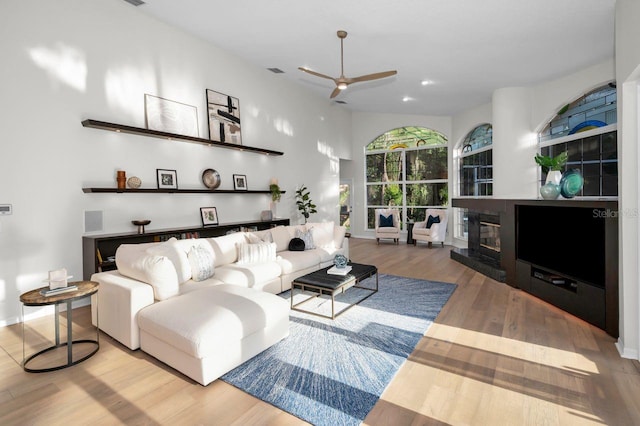4962 Turtle Creek Trl, Oldsmar, FL 34677 - living area featuring a ceiling fan, wood finished floors, a glass covered fireplace, baseboards, and recessed lighting