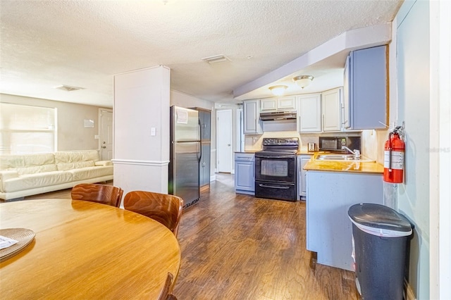 9020 Gray Fox Ln, Port Richey, FL 34668 - kitchen with black range with electric cooktop, freestanding refrigerator, under cabinet range hood, dark wood-style floors, and a sink