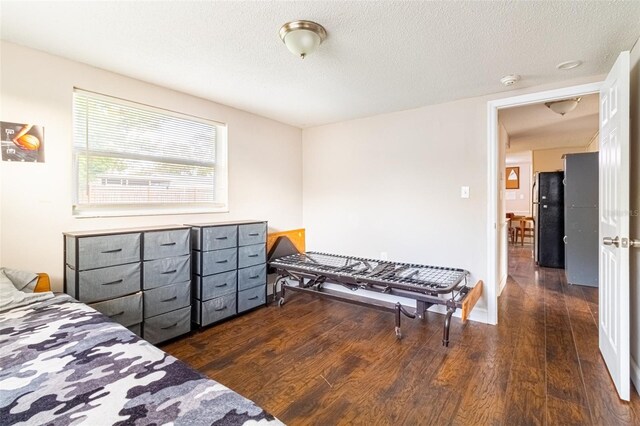 9020 Gray Fox Ln, Port Richey, FL 34668 - bedroom with freestanding refrigerator, dark wood-type flooring, and a textured ceiling