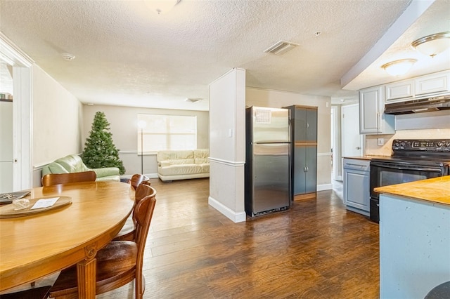 9020 Gray Fox Ln, Port Richey, FL 34668 - kitchen with freestanding refrigerator, black electric range oven, under cabinet range hood, dark wood-type flooring, and a textured ceiling