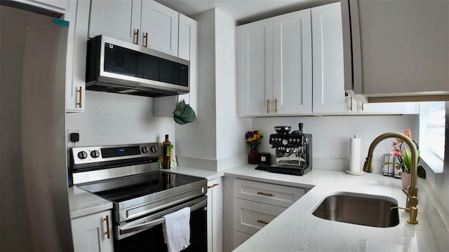 2219 Thrace St, Tampa, FL 33605 - kitchen featuring appliances with stainless steel finishes, a sink, white cabinetry, and light stone countertops