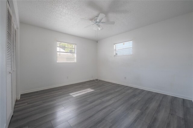 725 2nd Ave NE, Largo, FL 33770 - unfurnished bedroom featuring dark wood finished floors, a textured ceiling, a closet, a ceiling fan, and baseboards