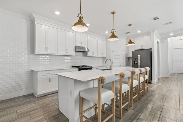 4345 Cadence Loop, Land O Lakes, FL 34638 - kitchen with stainless steel appliances, under cabinet range hood, baseboards, white cabinetry, and recessed lighting