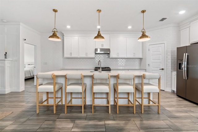 4345 Cadence Loop, Land O Lakes, FL 34638 - kitchen featuring appliances with stainless steel finishes, under cabinet range hood, light countertops, white cabinets, and backsplash