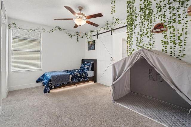 4345 Cadence Loop, Land O Lakes, FL 34638 - carpeted bedroom with a barn door, a ceiling fan, and baseboards