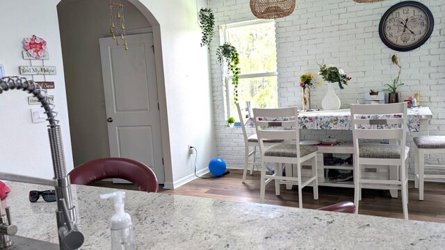 3446 Suncoast Plains Dr, Odessa, FL 33556 - dining area featuring wood finished floors, baseboards, arched walkways, and brick wall