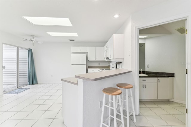 1624 Lullwater Ln, Lutz, FL 33549 - kitchen featuring white appliances, light tile patterned floors, a kitchen bar, a skylight, and recessed lighting