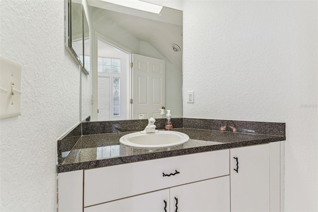 1624 Lullwater Ln, Lutz, FL 33549 - bathroom featuring a textured wall, vanity, and vaulted ceiling