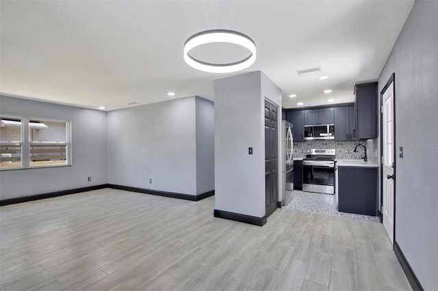 8603 N 9th St, Tampa, FL 33604 - kitchen with appliances with stainless steel finishes, light countertops, decorative backsplash, light wood finished floors, and baseboards