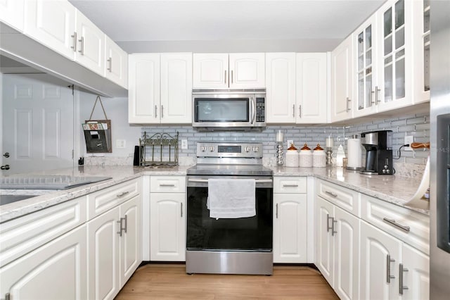 2311 64th Street Ct W, Bradenton, FL 34209 - kitchen featuring stainless steel appliances, light wood-style flooring, glass insert cabinets, white cabinetry, and tasteful backsplash