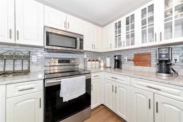 2311 64th Street Ct W, Bradenton, FL 34209 - kitchen with stainless steel appliances, decorative backsplash, white cabinetry, and glass insert cabinets