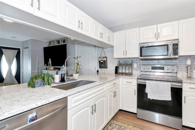 2311 64th Street Ct W, Bradenton, FL 34209 - kitchen with stainless steel appliances, a sink, light stone countertops, and white cabinetry