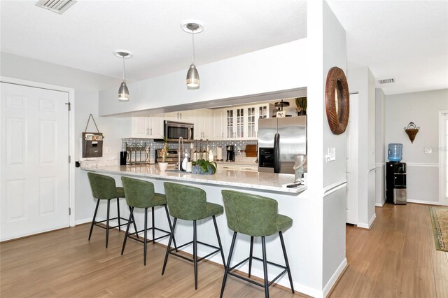 2311 64th Street Ct W, Bradenton, FL 34209 - kitchen featuring stainless steel appliances, a peninsula, decorative backsplash, light wood-style flooring, and glass insert cabinets